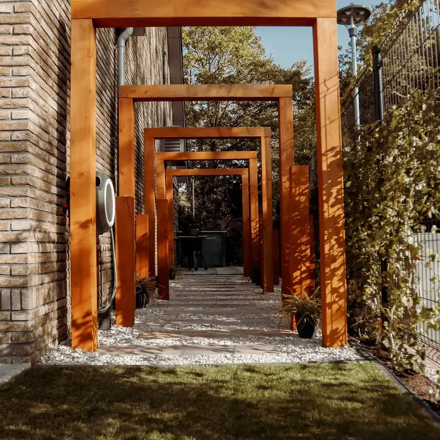 Strakke tuin met sfeervolle houten poortconstructie en buitenkeuken