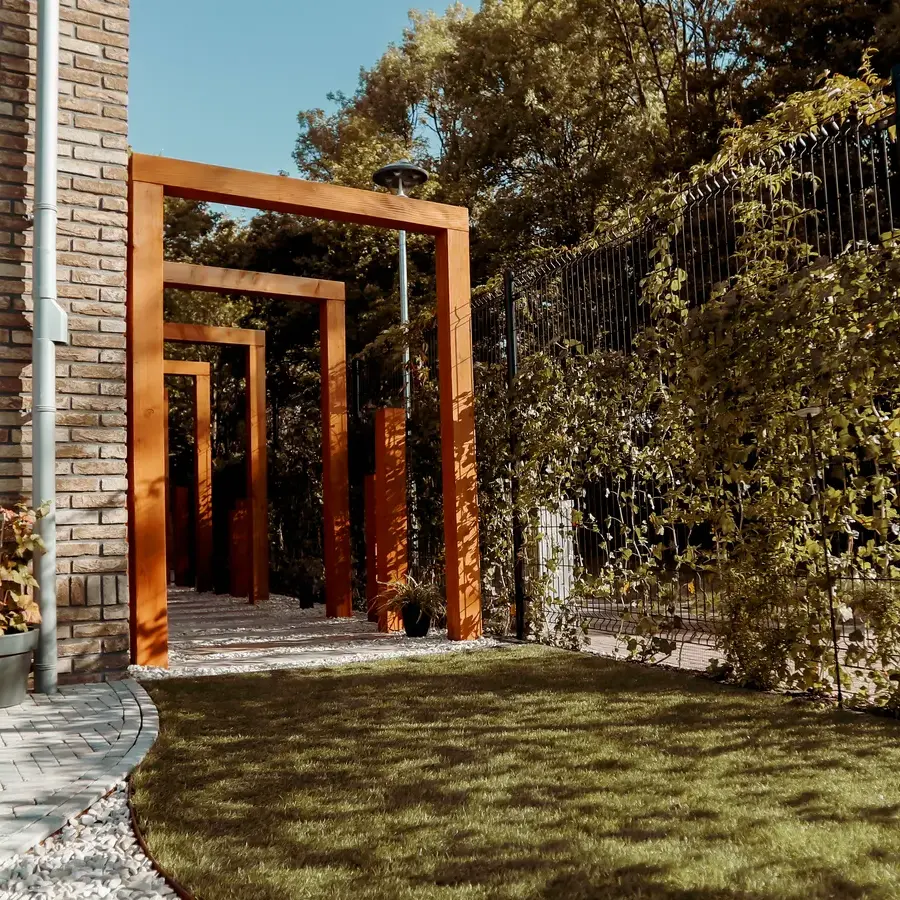 Strakke tuin met sfeervolle houten poortconstructie en buitenkeuken