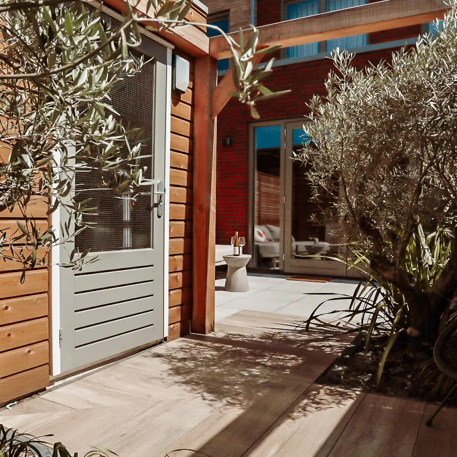 Compacte stadstuin met houten tuinhuis, pergola en mediterrane planten