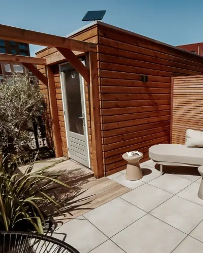 Compacte stadstuin met houten tuinhuis, pergola en mediterrane planten