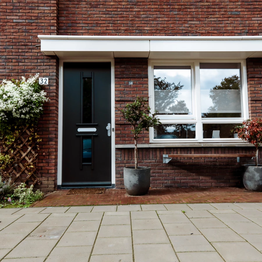 Voortuin met bankje, twee grote potten en border met klimplant