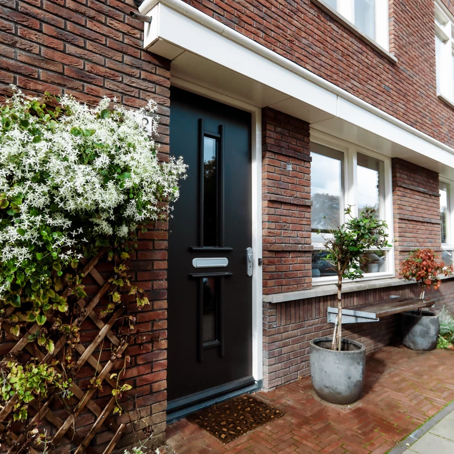 Voortuin met bankje, twee grote potten en border met klimplant