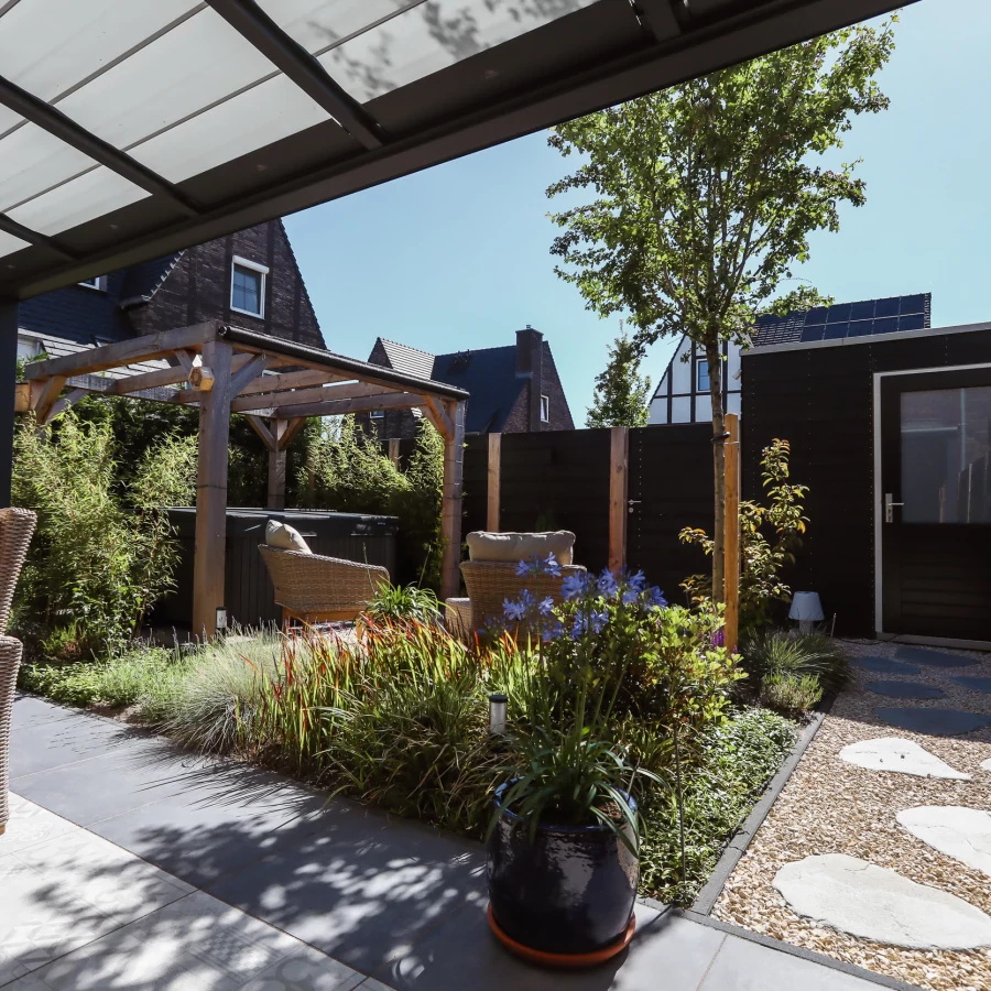 Stadstuin met veel groen rondom de jacuzzi onder een pergola