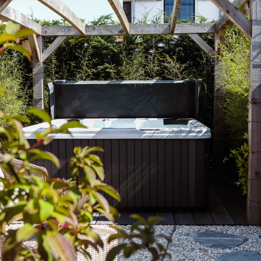 Stadstuin met veel groen rondom de jacuzzi onder een pergola