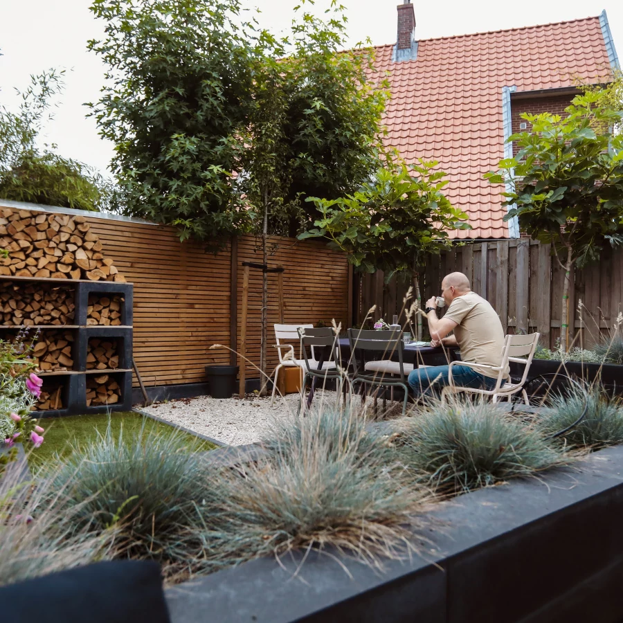 Knusse stadstuin omring door hoge borders en bomen