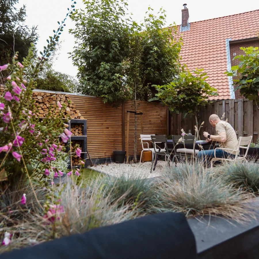 Knusse stadstuin omring door hoge borders en bomen