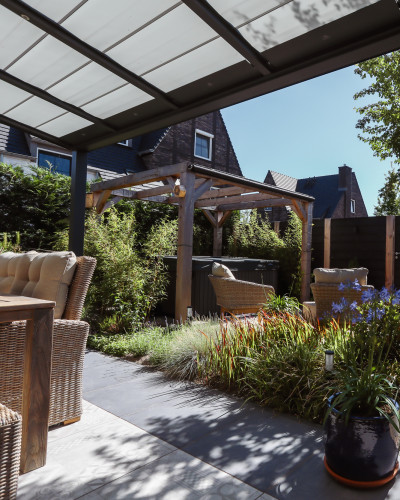 Stadstuin met veel groen rondom de jacuzzi onder een pergola