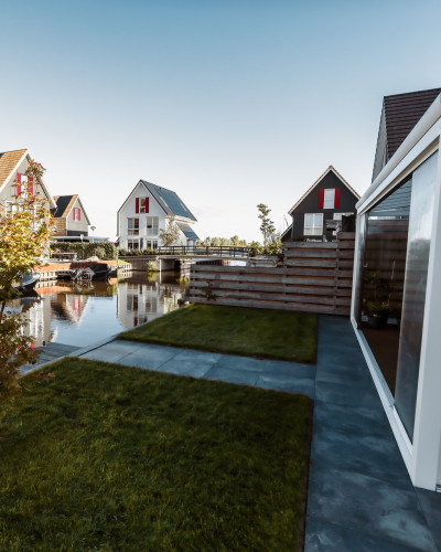 Compacte tuin aan het water met serre en aanlegsteiger